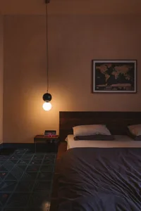 A minimalist bedroom featuring wooden furniture and a hanging light fixture.