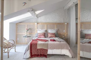 A minimalist bedroom with a wooden bed frame, textured walls, and simple decor.
