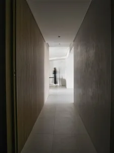 Minimalist corridor with wooden walls and a person walking on the floor.