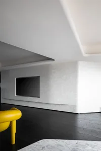 A minimalist living room features a sleek, modern design with white and black tones, accentuated by a bright yellow chair and