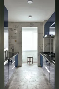 Modern minimalist residential kitchen with marble countertops and flooring, featuring a central window and stools.