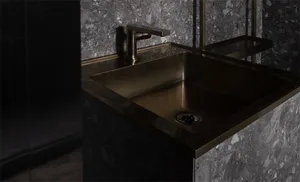 A modern bathroom featuring a brass sink and marble tiles.