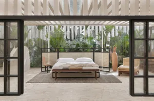 Modern bedroom featuring a wooden bed frame with white bedding, and a wooden bench at the foot of the bed, set against a back