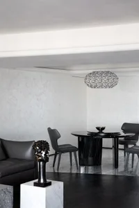 Modern dining room featuring a black marble dining table, metal chairs, and a geometric glass chandelier.