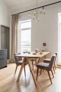 A modern dining room featuring a wooden table and chairs, with a minimalist design and warm lighting.
