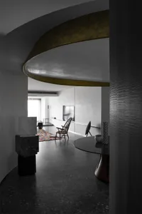 A modern interior featuring concrete elements, minimalist furniture, and a circular architectural design.