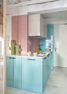 A modern kitchen with light blue cabinets and pink tiled walls.