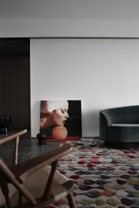 A modern living room with a gray velvet sofa and a colorful abstract rug.