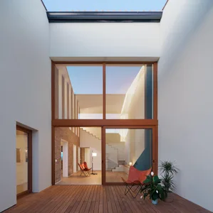 A modern living room with wooden flooring and large windows.