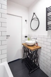 Modern minimalist bathroom featuring a wooden countertop on a metal base, white subway tiles, and a white sink with a round m