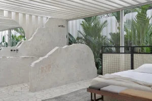 A minimalist bedroom featuring a stone tub and greenery outside.