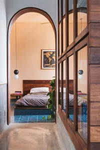 A minimalist bedroom with wooden furniture, concrete floor, and a green plant.