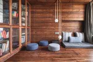 A minimalist living room with wood-paneled walls, a bookshelf, and seating area.