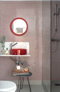 Modern bathroom featuring glass tiles on the walls and a red circular vessel sink.