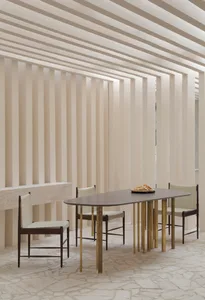 Modern dining room featuring wooden and brass furniture, with a minimalist design aesthetic.