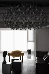 Minimalist interior design featuring a concrete floor with a large, artistic skull sculpture and a sleek black sofa.