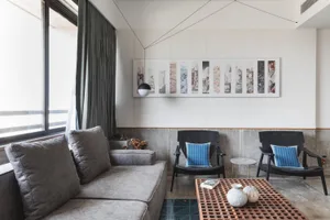 A modern living room with concrete and wooden elements, featuring a large window and minimalist furniture.