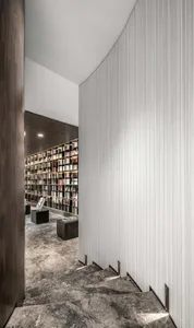 A modern library staircase made of marble with a view of a bookshelf.