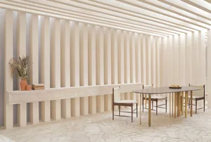 A modern restaurant interior with stone walls and floor, white slatted walls, and minimalist furniture.