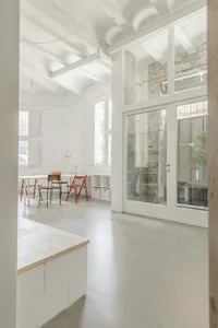 Modern minimalist office space with concrete walls, glass door, and wooden furniture.