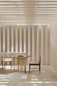 A modern minimalist dining room features stone accents and a metal dining table with minimalist white chairs.