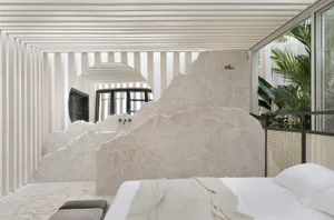 A serene modern bedroom with stone walls and a minimalist design.
