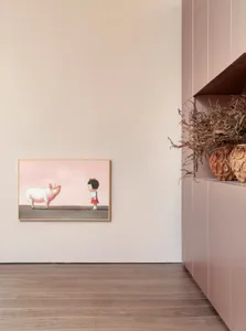 A minimalist painting featuring a girl standing next to a pink pig, displayed in a modern, neutral-toned room.