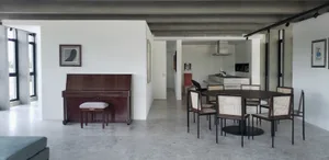 Modern, minimalist living room with a large window, concrete floor, and black furniture.