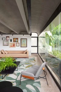 A modern living room featuring a concrete ceiling, glass walls, and green plants.