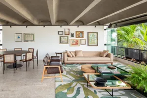 A modern living room featuring a concrete floor and walls, with a beige sofa and abstract art on the walls.