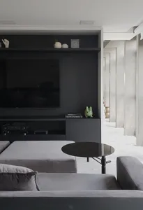 A modern minimalist living room featuring a sleek black entertainment center, grey furniture, and a round black coffee table