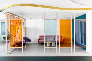Modern office lobby with colorful transparent glass walls and contemporary furniture.