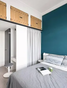 A minimalist bedroom featuring a grey bed with white fabric bedding and wooden accents.