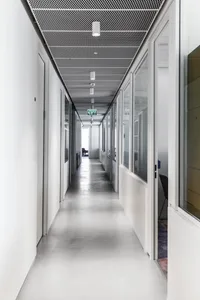 A minimalist office corridor with concrete flooring and white walls.