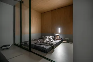 A minimalist bedroom featuring a wooden bed and sleek design.