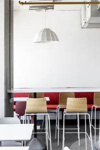 White pendant light above a long red bench seat in a modern cafe interior design.