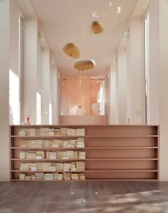 A minimalist library with wooden shelves and soft lighting features.
