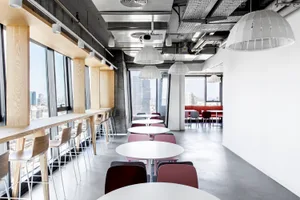 Modern collaborative office space with concrete flooring and minimalistic design.