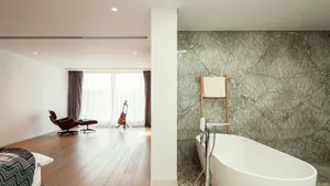 A modern bathroom with marble walls and a white freestanding bathtub.
