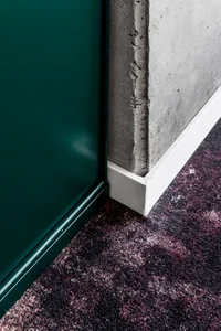 A modern, minimalist interior space featuring exposed concrete walls and dark green cabinetry.