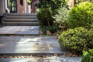 Concrete steps and landscaping with rocks and greenery in a modern outdoor setting.