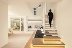 A modern home with a concrete staircase illuminated by built-in lighting.
