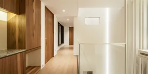 A modern interior corridor featuring wood, steel, and concrete elements.