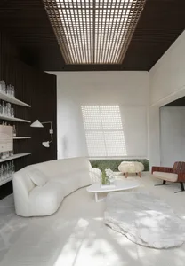 A contemporary living room featuring a sleek, white leather sofa against a minimalist backdrop with a white, textured rug and
