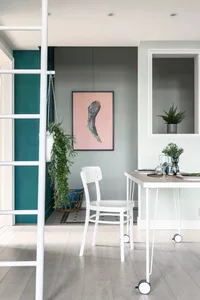 A modern residential dining room featuring a wooden floor, white furniture, and greenery.