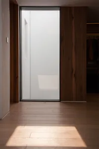 Minimalist interior design featuring a frosted glass wall and wooden floor.