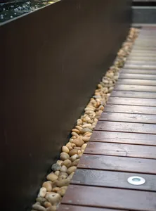 A minimalist landscape design featuring a wooden walkway bordered by smooth rocks.