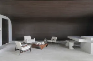 A modern living room with minimalist decor, featuring concrete walls and wooden furniture.