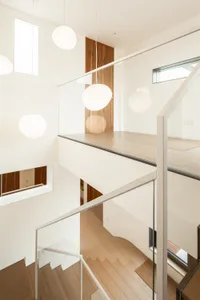 Modern interior staircase made of wood with glass railings and pendant lights.