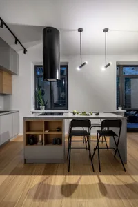 Modern kitchen interior with a marble countertop and wooden cabinets.